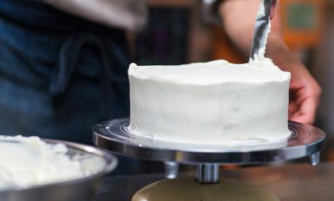 Crumb coat of icing being applied to a cake before decorating.